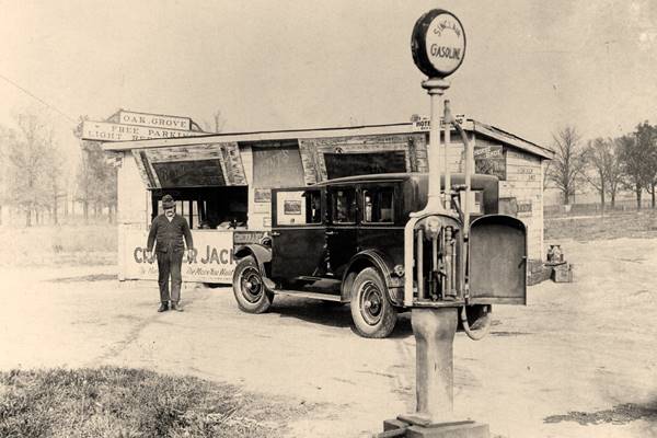 black and white 1922, man by a small woodframe building, store with Sinclair gas pump